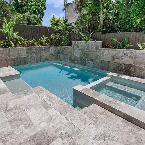 silver travertine tiles laid around a pool